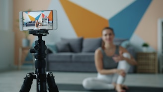 Woman recording fitness video on phone with tripod.