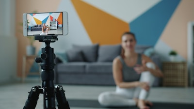 Woman recording fitness video on phone with tripod.