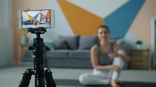 Woman recording fitness video on phone with tripod.