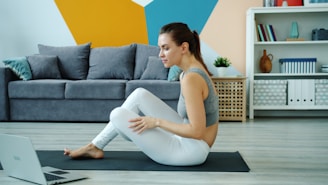 Woman exercising on yoga mat watching laptop