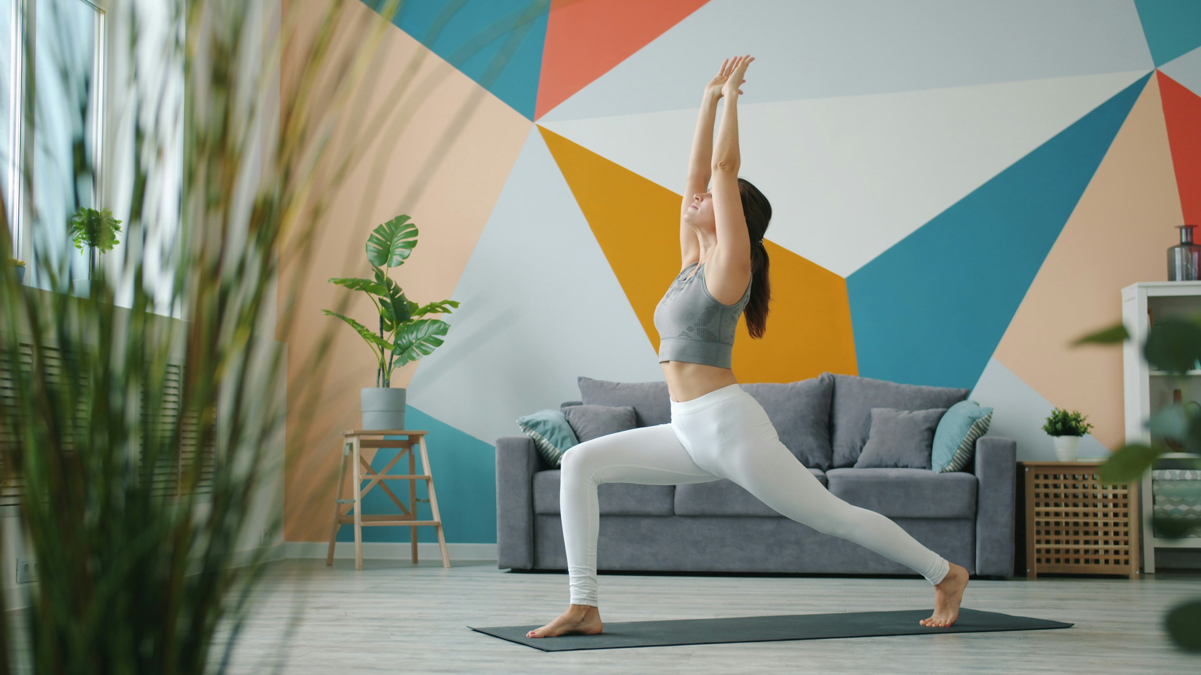 Woman practicing yoga in a modern living room.
