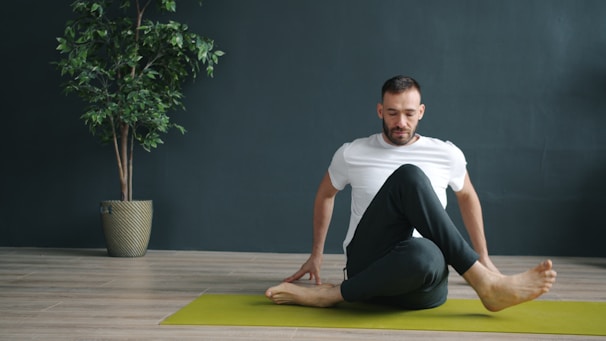 Man practicing yoga asana on a mat indoors.