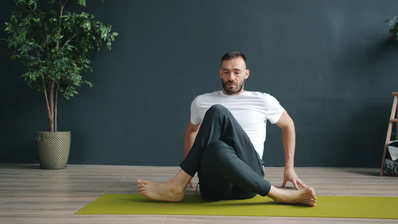 Patient sitting upright in a seated spinal twist on a mat, showing strong posture and a pain-free back after physical therapy