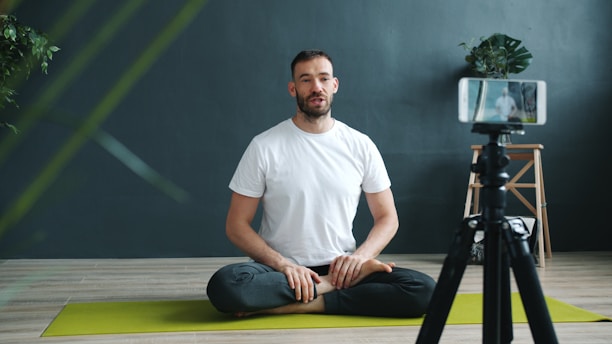 Man meditating in front of a phone camera