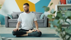 Man meditating in lotus position on yoga mat.