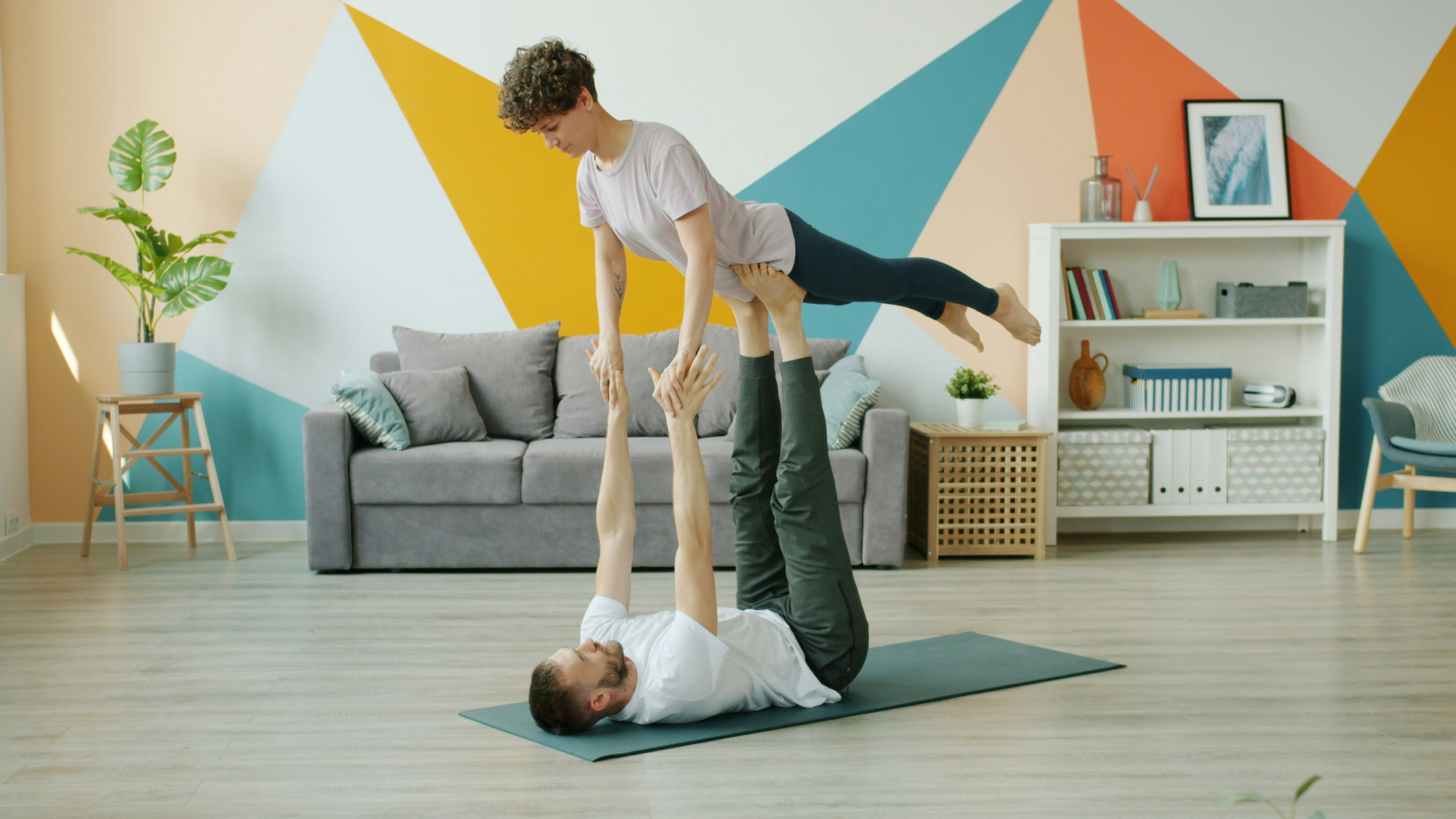 Two people doing acroyoga on a mat indoors.