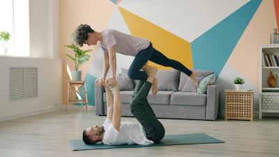 Couple doing acroyoga on a mat indoors.