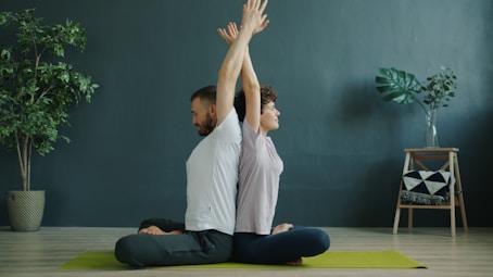 Couple meditating back to back on yoga mat