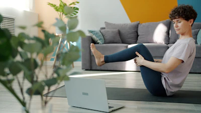 Woman doing yoga in front of a laptop