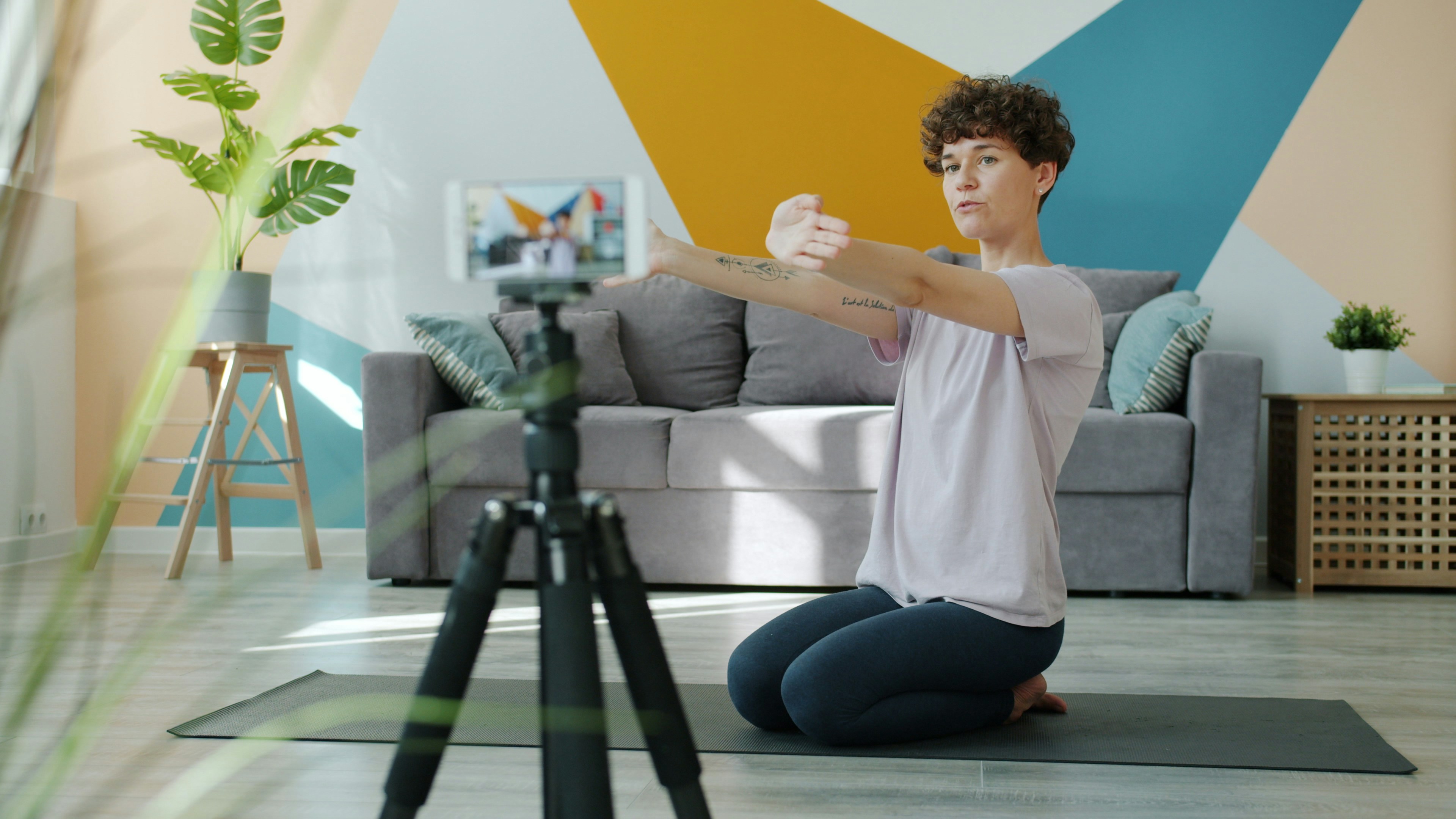 Woman doing yoga in front of a phone on tripod.
