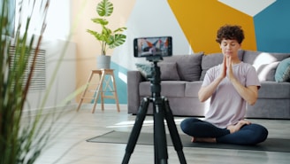 Woman meditating in front of a phone camera.