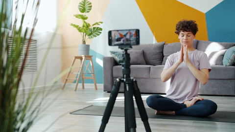 Woman meditating in front of a phone camera