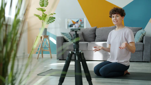Woman filming herself on a tripod in a living room.