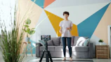 Woman records fitness video in living room.
