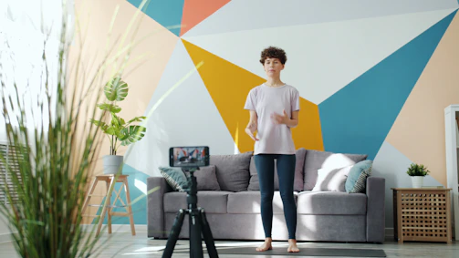 Woman records fitness video in living room.