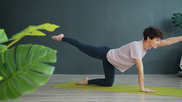 Woman practicing yoga on a mat indoors.