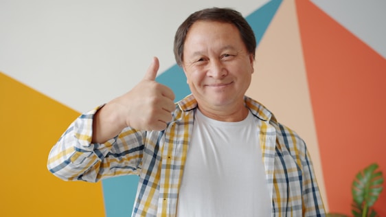 Smiling man gives a thumbs up gesture.