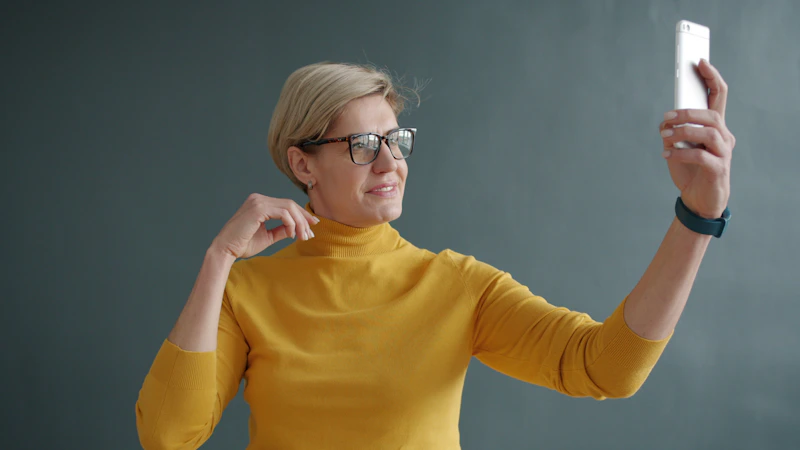 woman in a yellow turtleneck taking a selfie