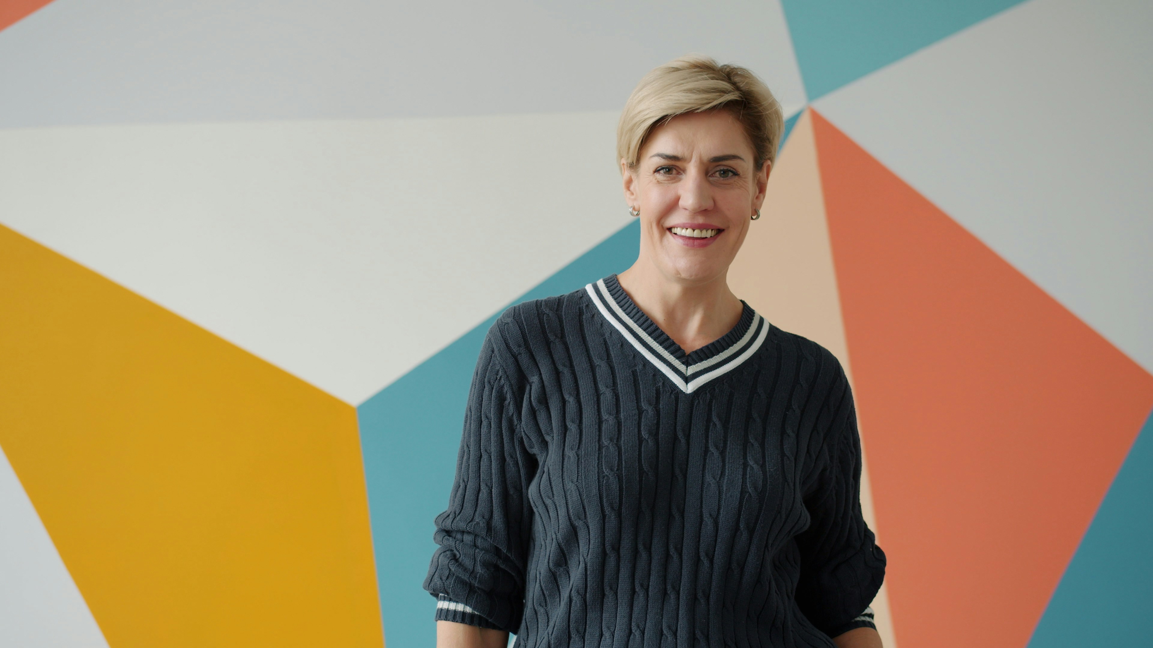 Frau lächelt vor bunter geometrischer Wand