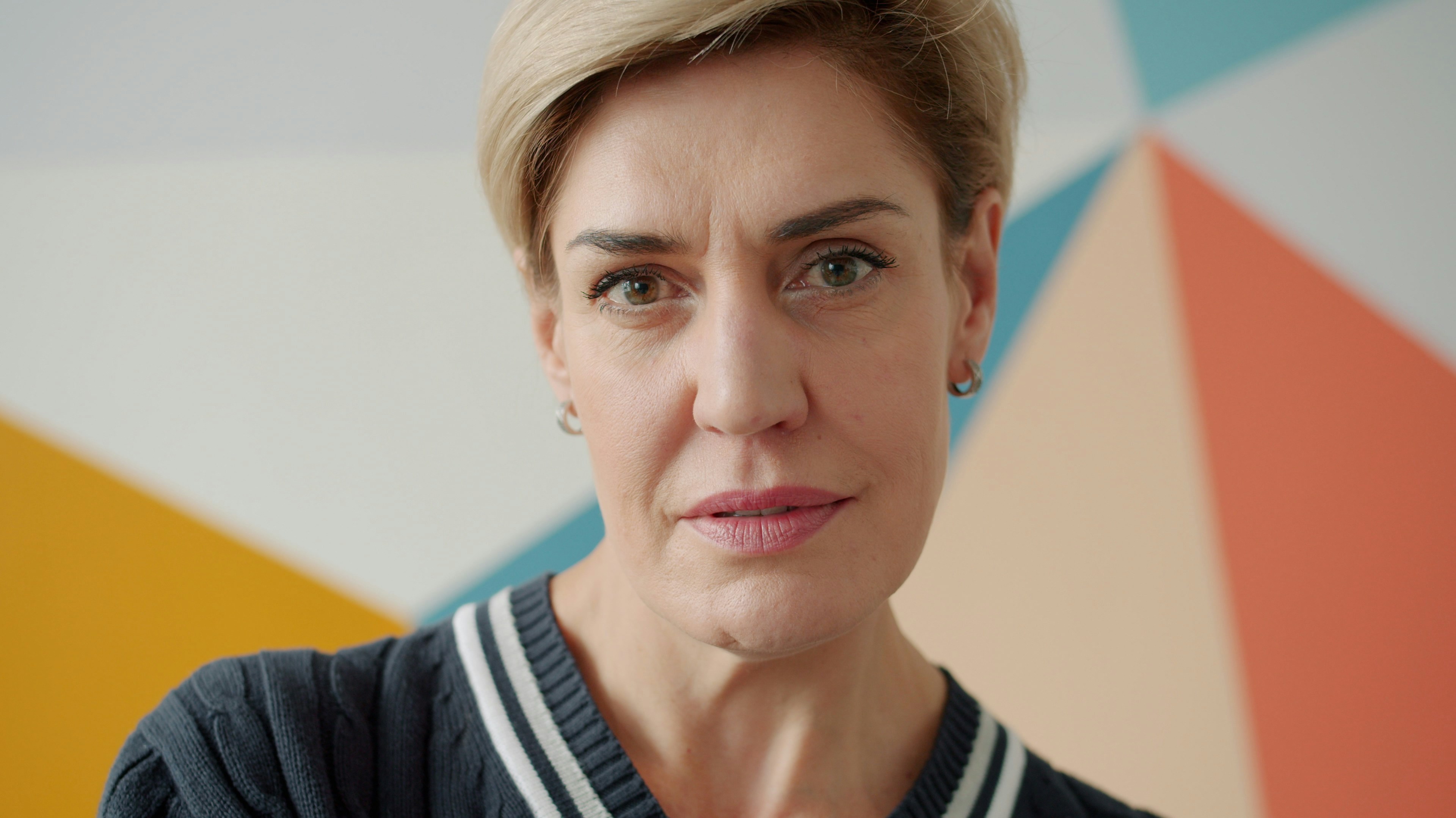 Mujer rubia con cabello corto mirando hacia adelante.