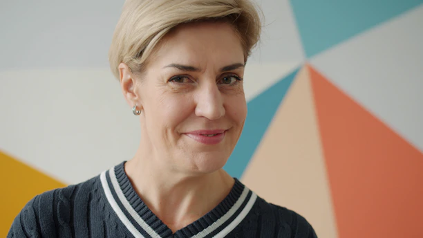 Blonde woman smiling against colorful geometric wall