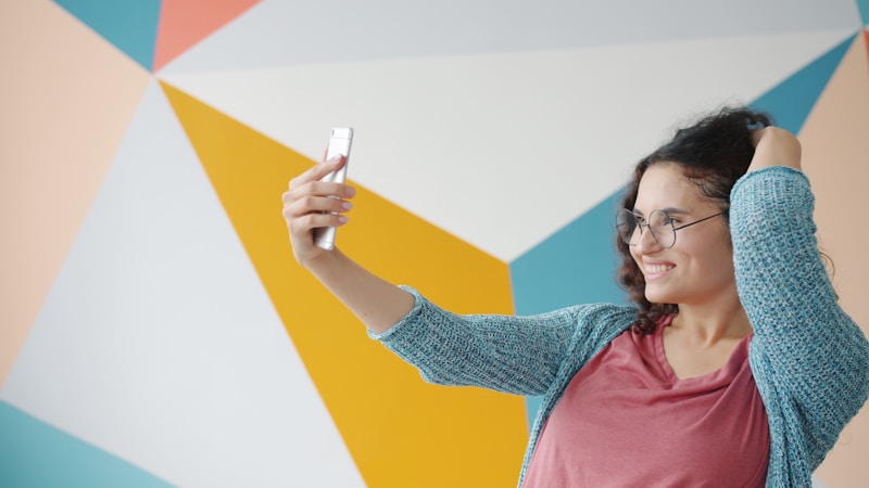 Fun sugar mama taking selfie against geometric wall