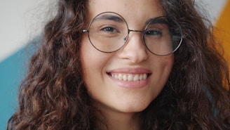 Young woman with curly hair and glasses smiling