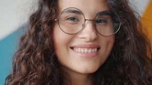 Young woman with curly hair and glasses smiling
