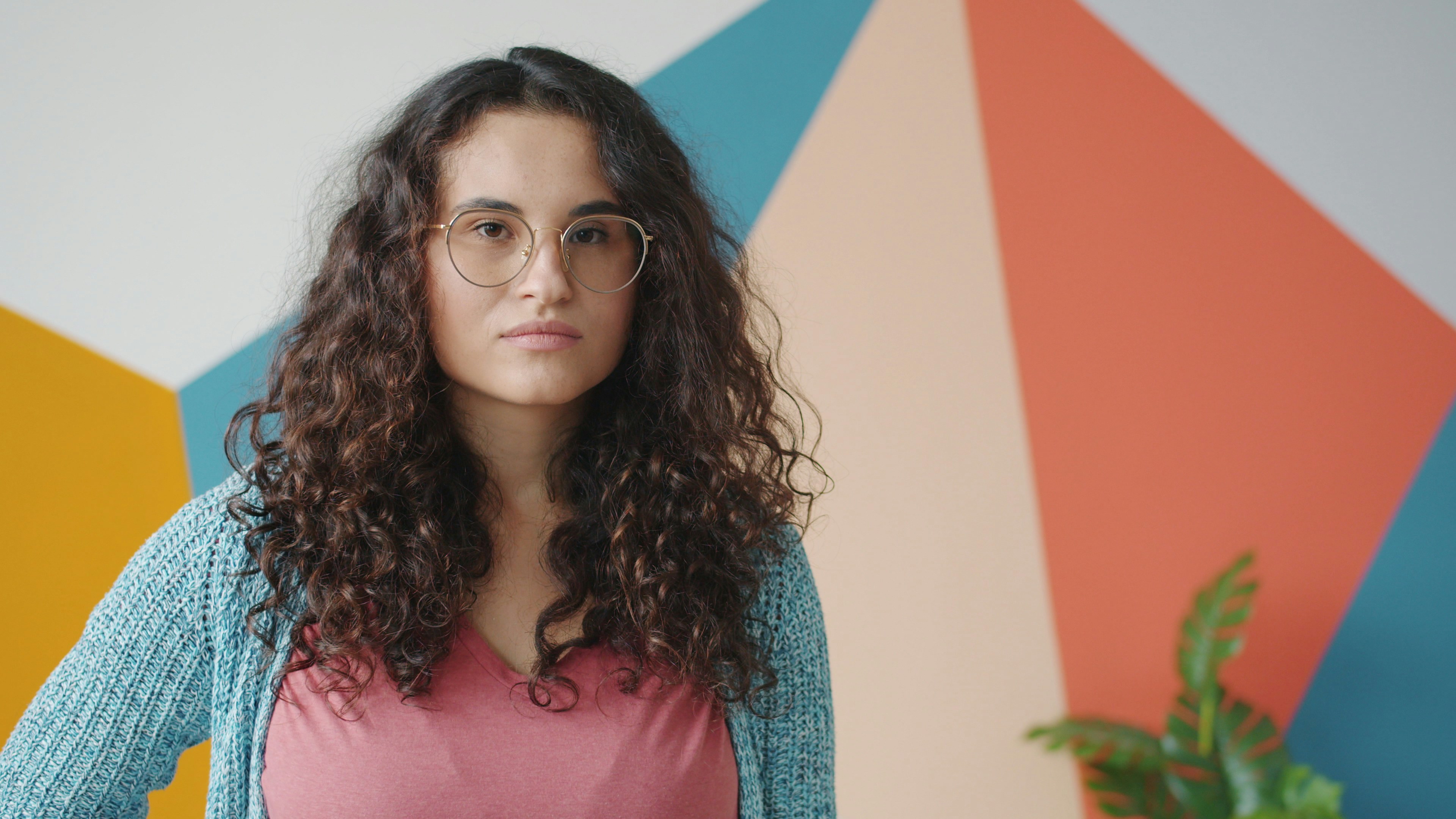 Woman with curly hair wearing glasses and cardigan.