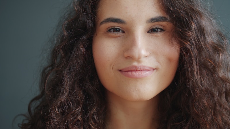 młoda kobieta z kręconymi włosami uśmiecha się delikatnie