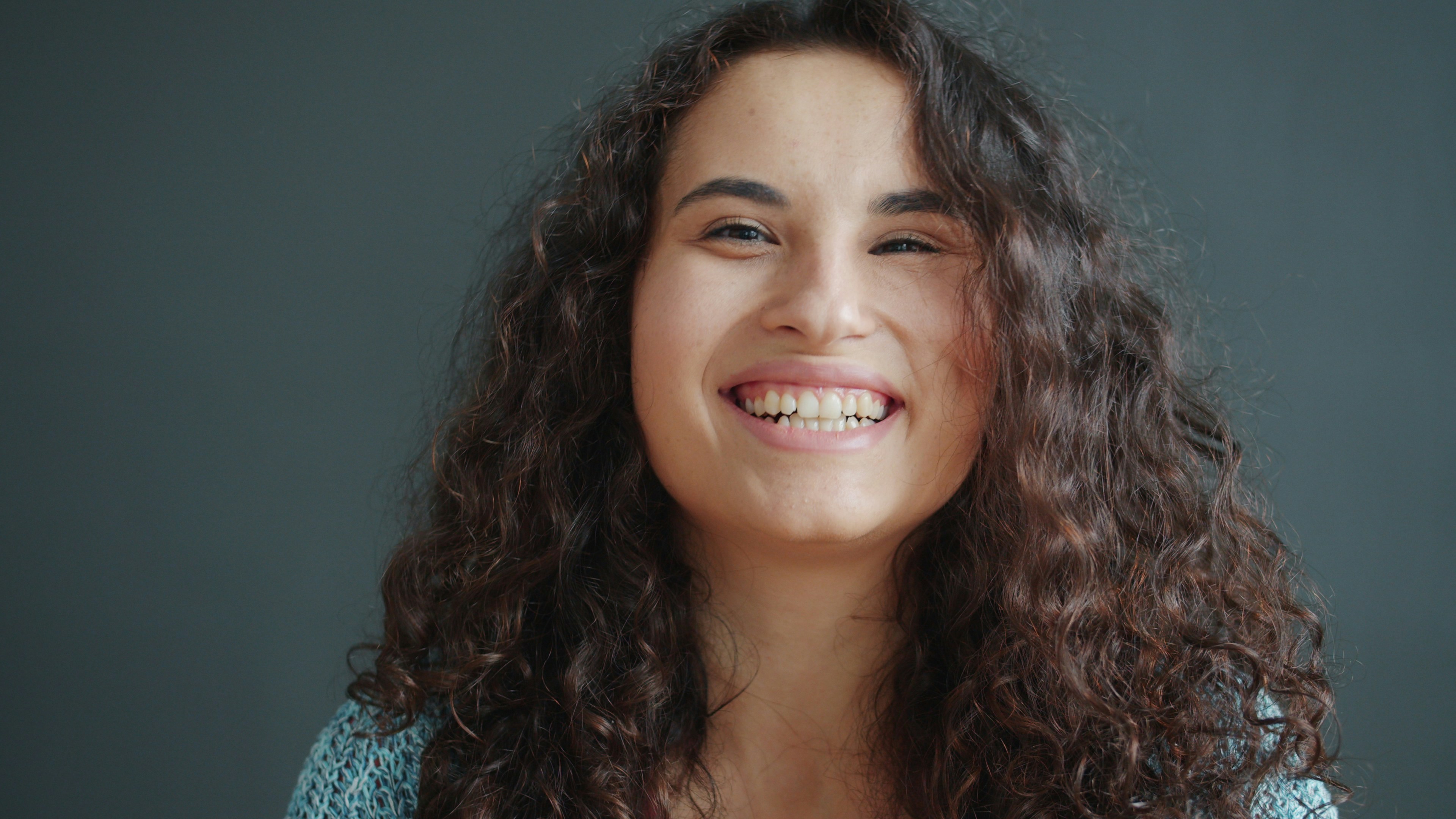 A young woman with curly hair laughing heartily