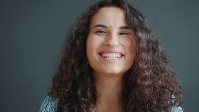 A young woman with curly hair laughing heartily.
