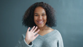 Young woman waving hello with a smile