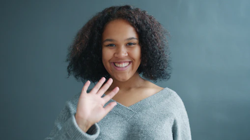 Young woman waving hello with a smile