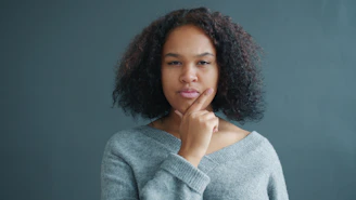 Young woman with hand on chin, looking thoughtful.