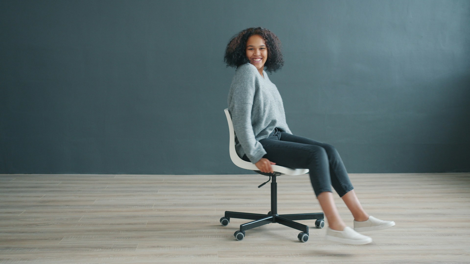 Young woman sitting on office chair, smiling at camera