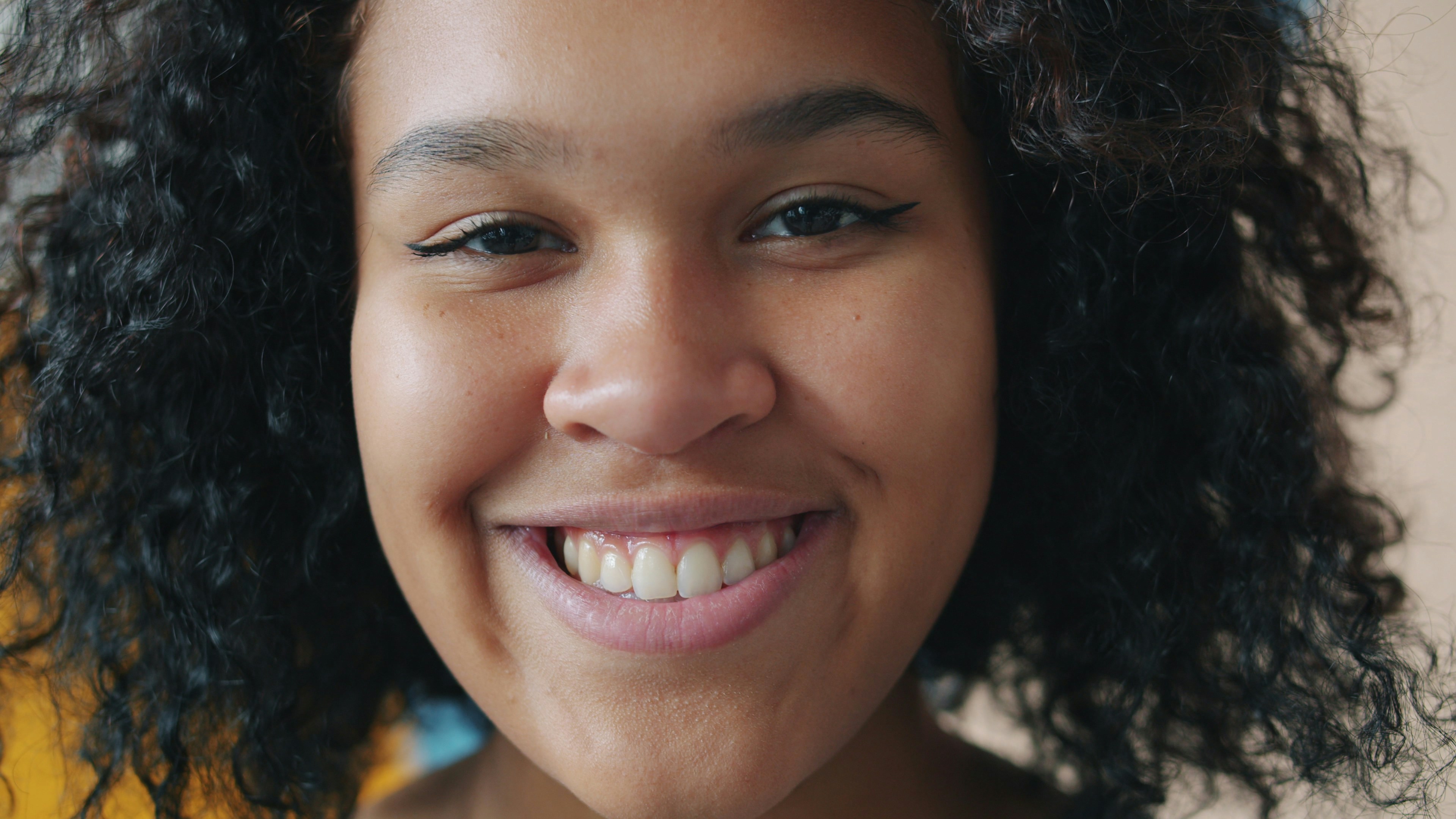 A young woman with curly hair smiling widely