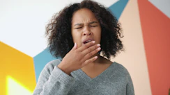 Young woman yawning with hand over mouth