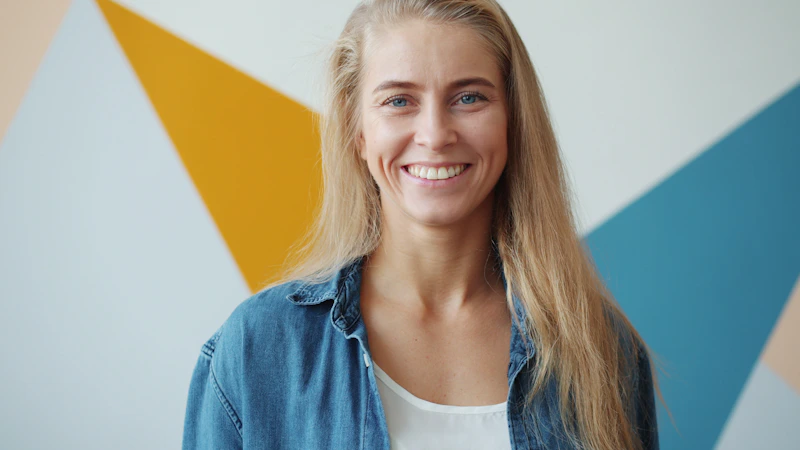blonde woman smiling by a geometric wall