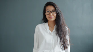 Woman with glasses wearing a white shirt.
