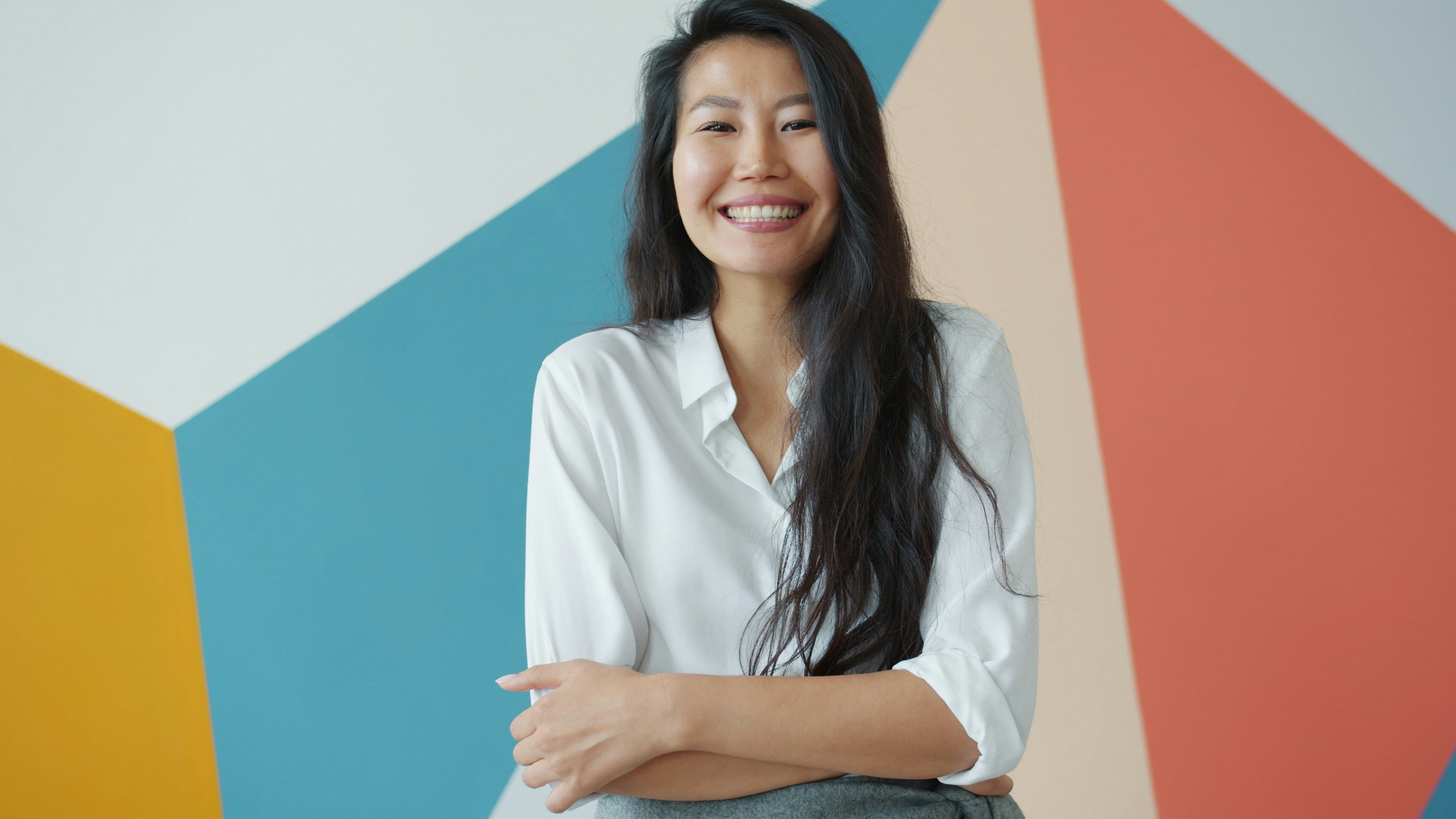 Smiling woman in white shirt against colorful wall