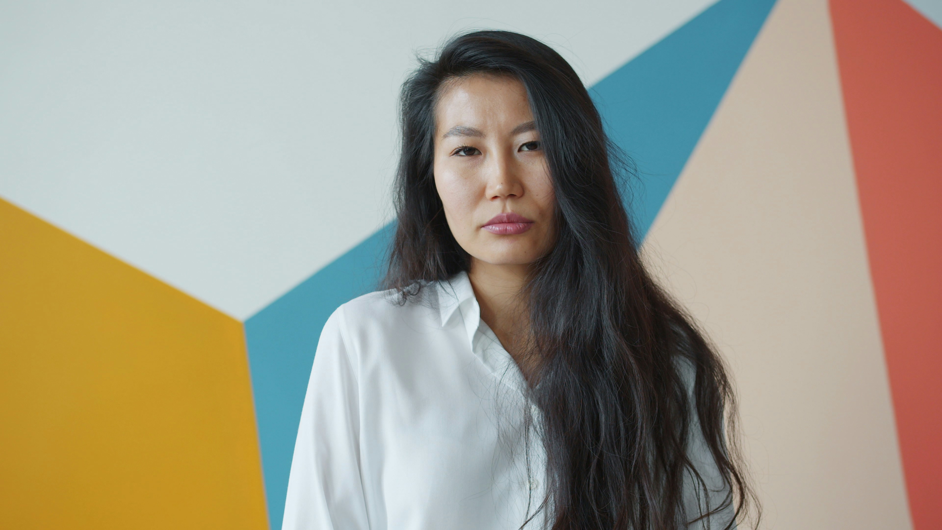 Woman with long dark hair against colorful wall