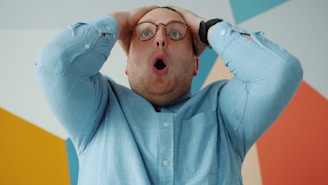 Man with glasses grabs head in shock