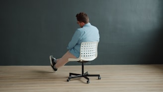 Man sitting on office chair with legs crossed.