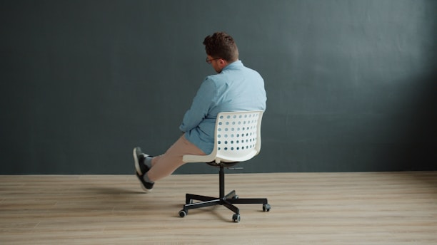 Man sitting on office chair with legs crossed.