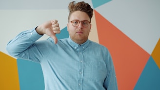 Man with glasses gives a thumbs down gesture.