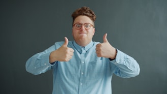 Man with glasses gives two thumbs up.