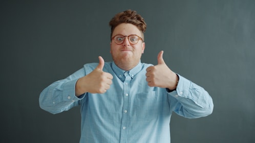 Man with glasses gives two thumbs up.