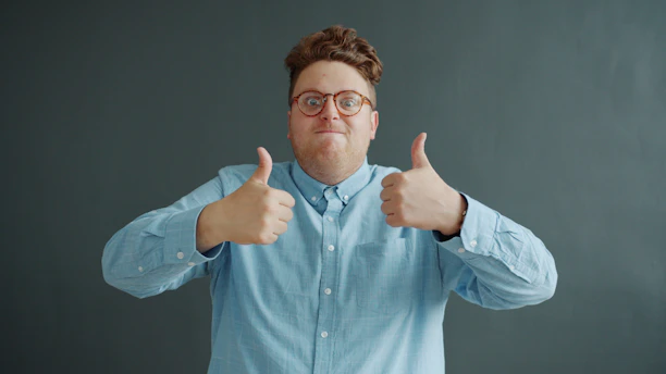 Man with glasses gives two thumbs up.