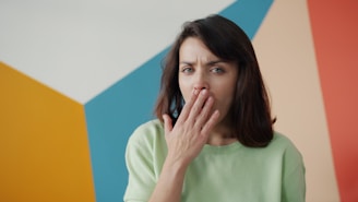 Woman covering mouth with hand, looking surprised.
